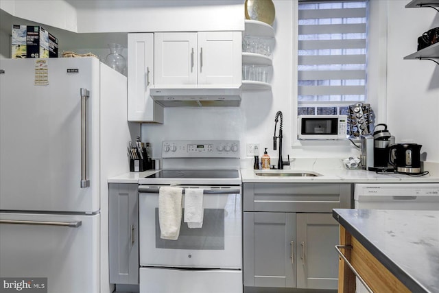 kitchen with white cabinets, sink, white appliances, range hood, and light stone countertops