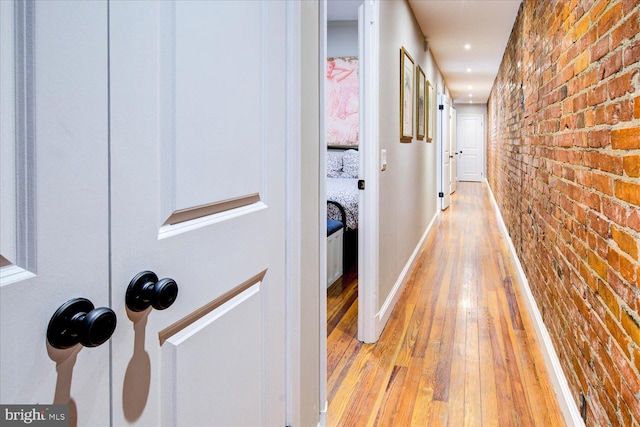 corridor with brick wall and light wood-type flooring