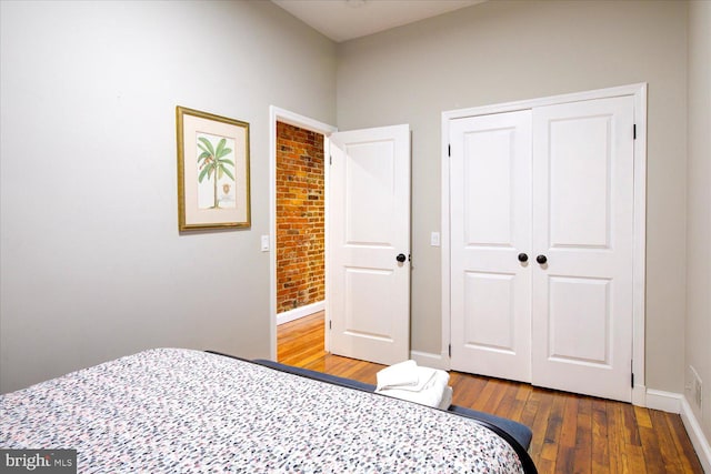 bedroom with brick wall, a closet, and hardwood / wood-style flooring