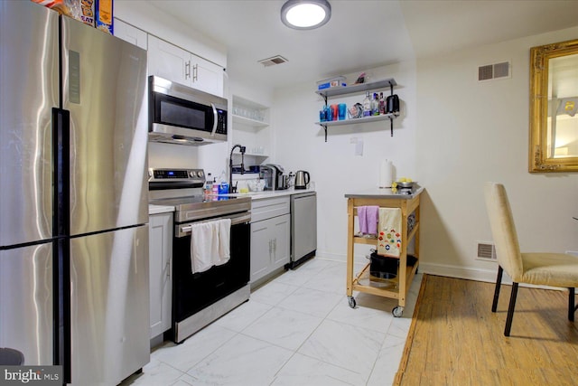 kitchen with light hardwood / wood-style flooring, appliances with stainless steel finishes, sink, and white cabinetry