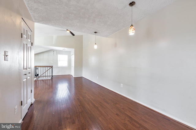 spare room with dark wood-type flooring, a textured ceiling, and vaulted ceiling