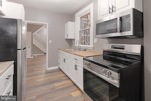 kitchen featuring stainless steel appliances, light wood-type flooring, sink, and white cabinetry