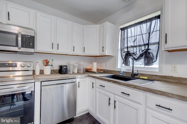 kitchen featuring dark tile patterned floors, white cabinetry, appliances with stainless steel finishes, and sink