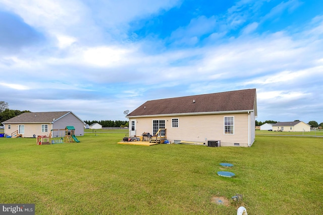 back of property with a lawn, a playground, and central AC unit