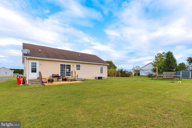 back of property featuring a storage unit, a trampoline, a patio area, and a yard