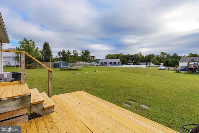 view of yard featuring a wooden deck, cooling unit, and a shed