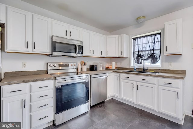 kitchen with appliances with stainless steel finishes, white cabinetry, and sink