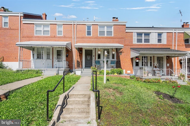 townhome / multi-family property with covered porch and a front yard