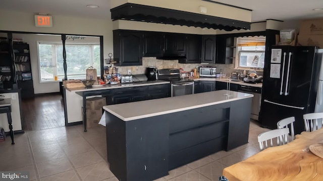 kitchen featuring light wood-type flooring, tasteful backsplash, sink, stainless steel appliances, and a center island