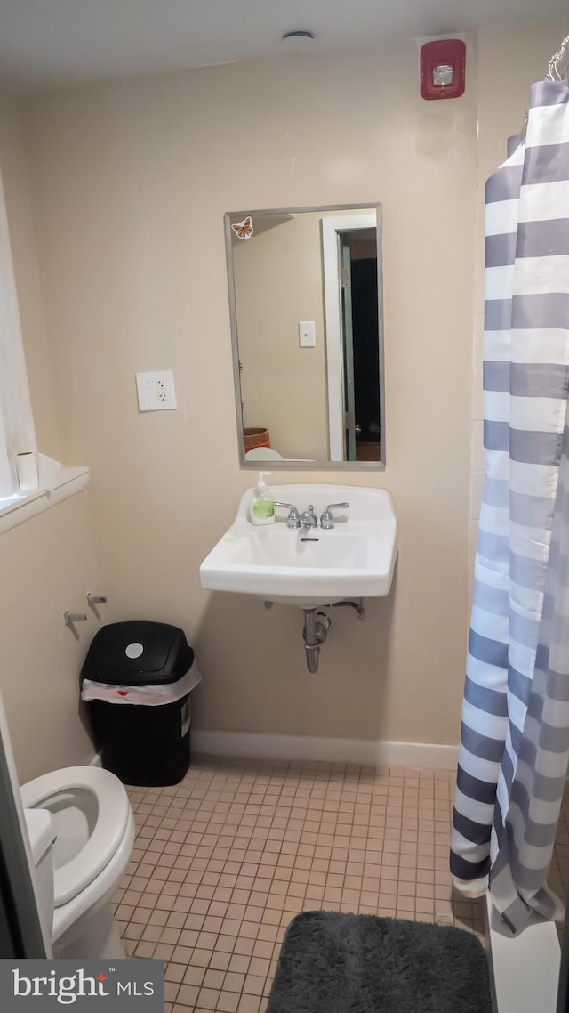 bathroom featuring a shower with curtain, sink, toilet, and tile patterned floors