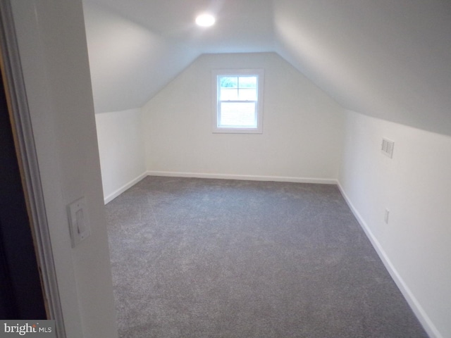 bonus room with dark colored carpet and vaulted ceiling