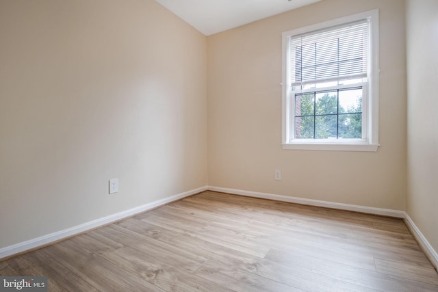 spare room with baseboards and wood finished floors