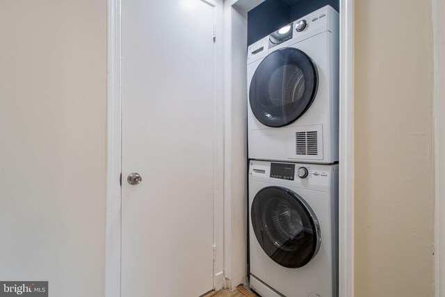 clothes washing area with stacked washer and dryer and laundry area