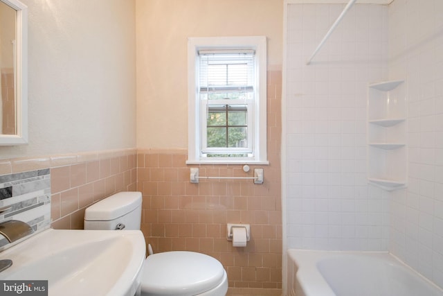 bathroom with tile walls, a sink, toilet, and shower / bathing tub combination