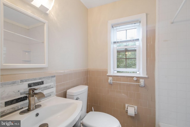 full bathroom featuring walk in shower, a sink, tile walls, toilet, and wainscoting