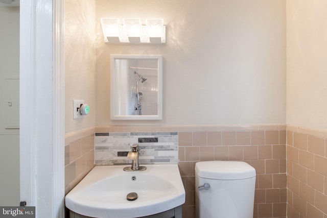 bathroom with tile walls, toilet, vanity, and wainscoting