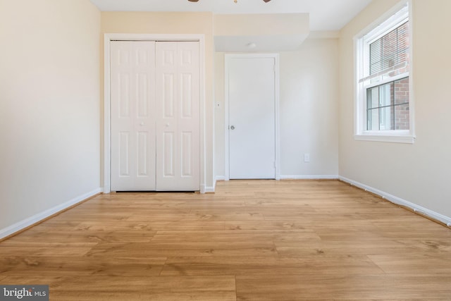 unfurnished bedroom with ceiling fan, light wood-type flooring, and a closet