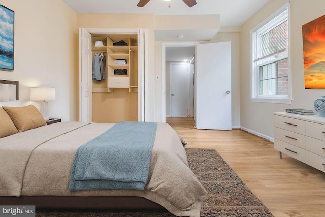 bedroom with a walk in closet, baseboards, light wood finished floors, and ceiling fan