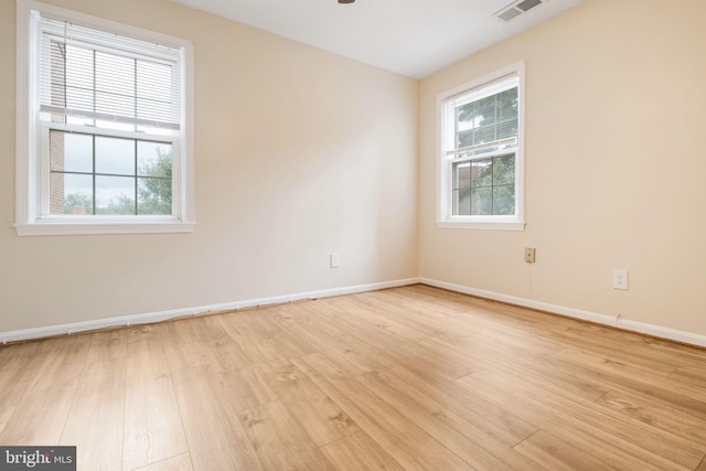 spare room with visible vents, baseboards, light wood-type flooring, and plenty of natural light