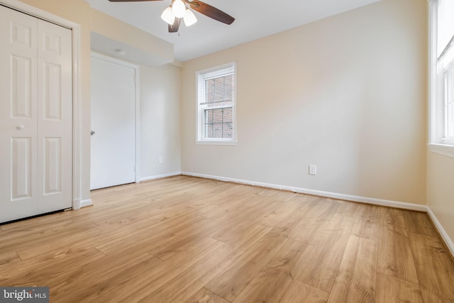 unfurnished bedroom with a closet, baseboards, ceiling fan, and light wood-style floors