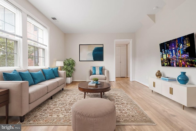 living room with visible vents, light wood-style flooring, and baseboards