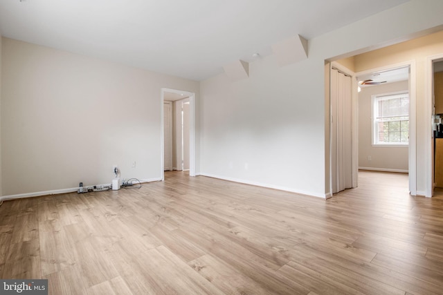 empty room with light wood-style floors, baseboards, and a ceiling fan