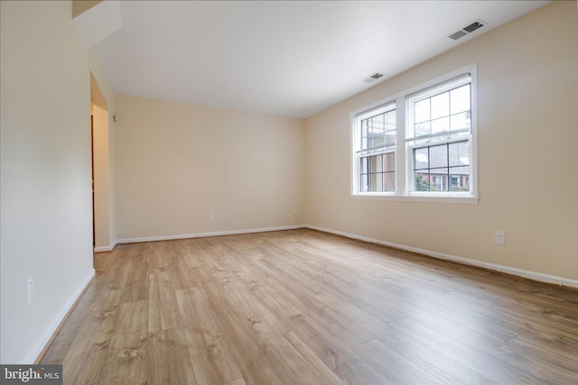 spare room with light wood-style floors, baseboards, and visible vents