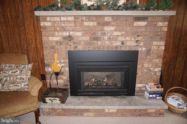 room details featuring a brick fireplace, carpet floors, and wood walls