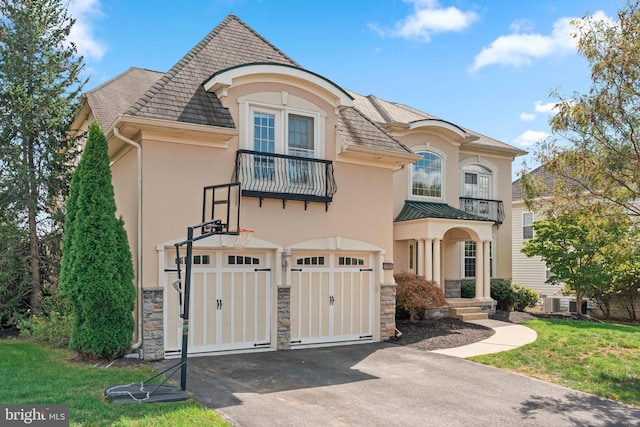 view of front of home featuring stone siding, a balcony, stucco siding, and aphalt driveway