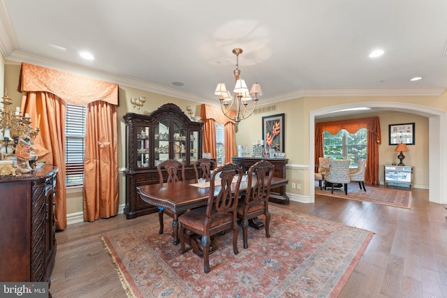 dining area featuring wood-type flooring, crown molding, and a notable chandelier