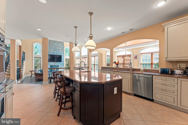 kitchen featuring a healthy amount of sunlight, dishwasher, light stone countertops, and a kitchen island with sink