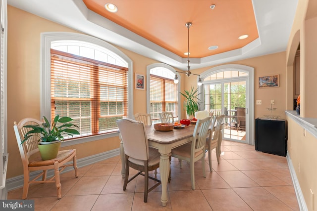 dining area with a raised ceiling, light tile patterned flooring, and plenty of natural light