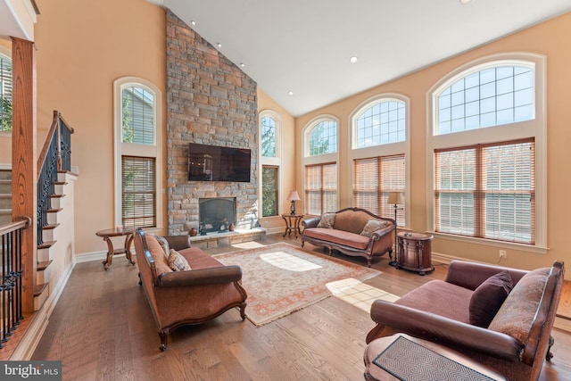 living room featuring high vaulted ceiling, hardwood / wood-style flooring, and a fireplace