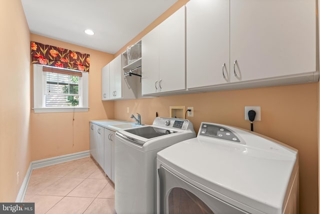 washroom featuring light tile patterned floors, baseboards, a sink, cabinet space, and washing machine and dryer