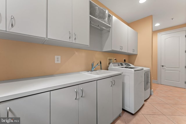 laundry area with washing machine and clothes dryer, sink, light tile patterned floors, and cabinets