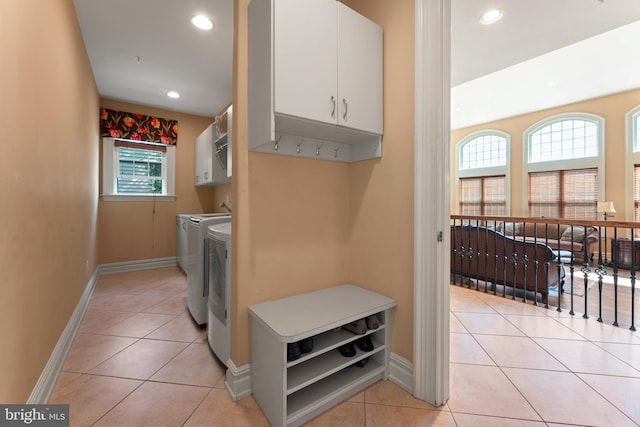 washroom with cabinets, light tile patterned floors, and washing machine and dryer