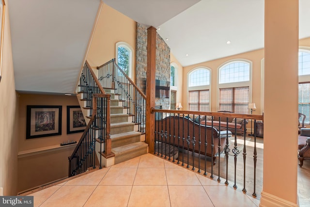 stairs with high vaulted ceiling, a wealth of natural light, and tile patterned floors