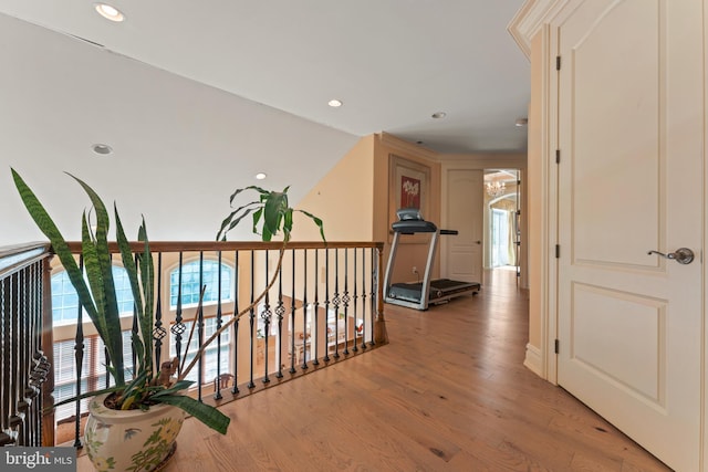corridor with an upstairs landing, light wood finished floors, and recessed lighting