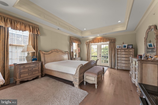 bedroom with a raised ceiling, ornamental molding, wood-type flooring, french doors, and access to exterior