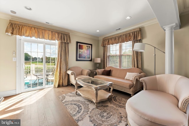 living room featuring light hardwood / wood-style floors, crown molding, and decorative columns