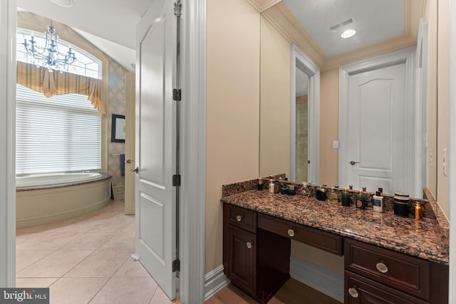 bathroom with a notable chandelier, tile patterned floors, a bath, and vanity