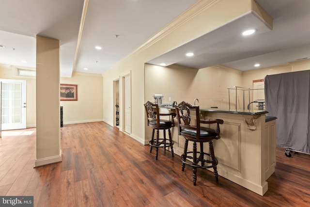 bar featuring recessed lighting, wet bar, ornamental molding, baseboards, and dark wood-style floors