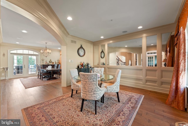 dining room with ornamental molding, wood-type flooring, and a notable chandelier