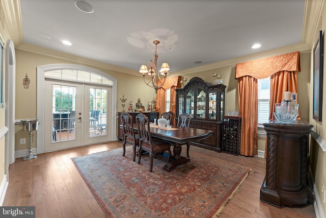 dining room featuring wood-type flooring, a notable chandelier, plenty of natural light, and crown molding