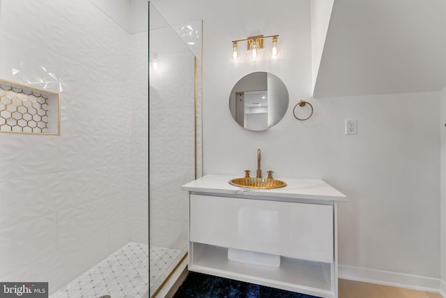 bathroom with a tile shower and vanity