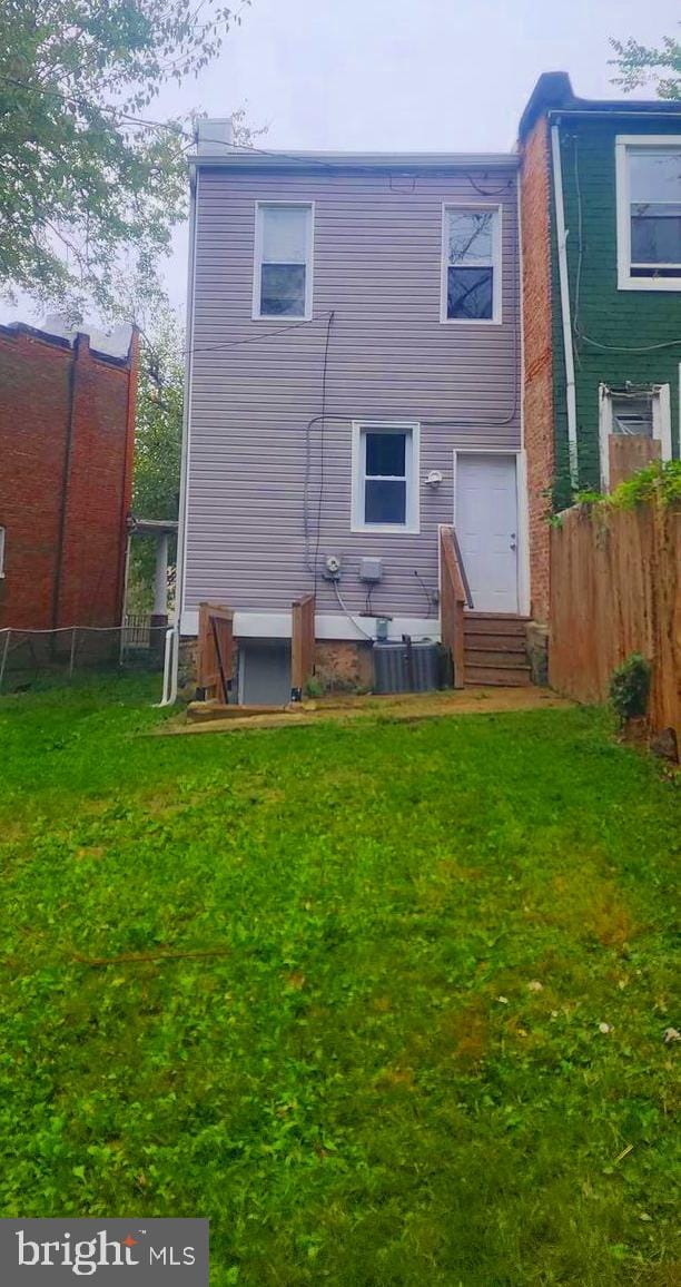 back of house with central AC unit and a lawn