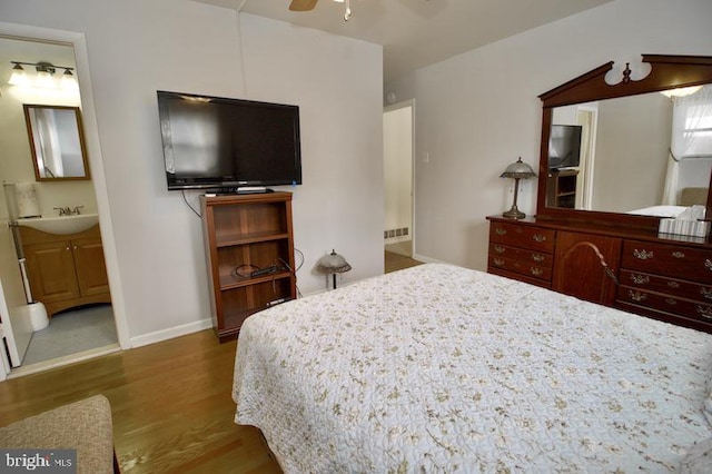 bedroom featuring wood-type flooring, ceiling fan, ensuite bathroom, and sink