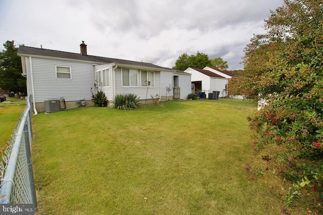 back of property featuring central AC unit and a lawn