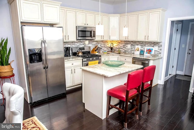 kitchen with appliances with stainless steel finishes, a center island, dark hardwood / wood-style flooring, and a kitchen breakfast bar