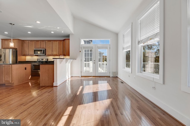 kitchen featuring vaulted ceiling, stainless steel appliances, light hardwood / wood-style floors, french doors, and decorative light fixtures